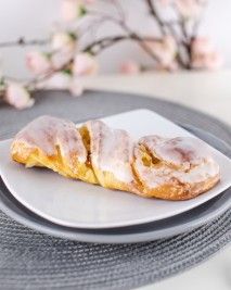 Pleciona drożdżówka z lukrem na białym talerzu
